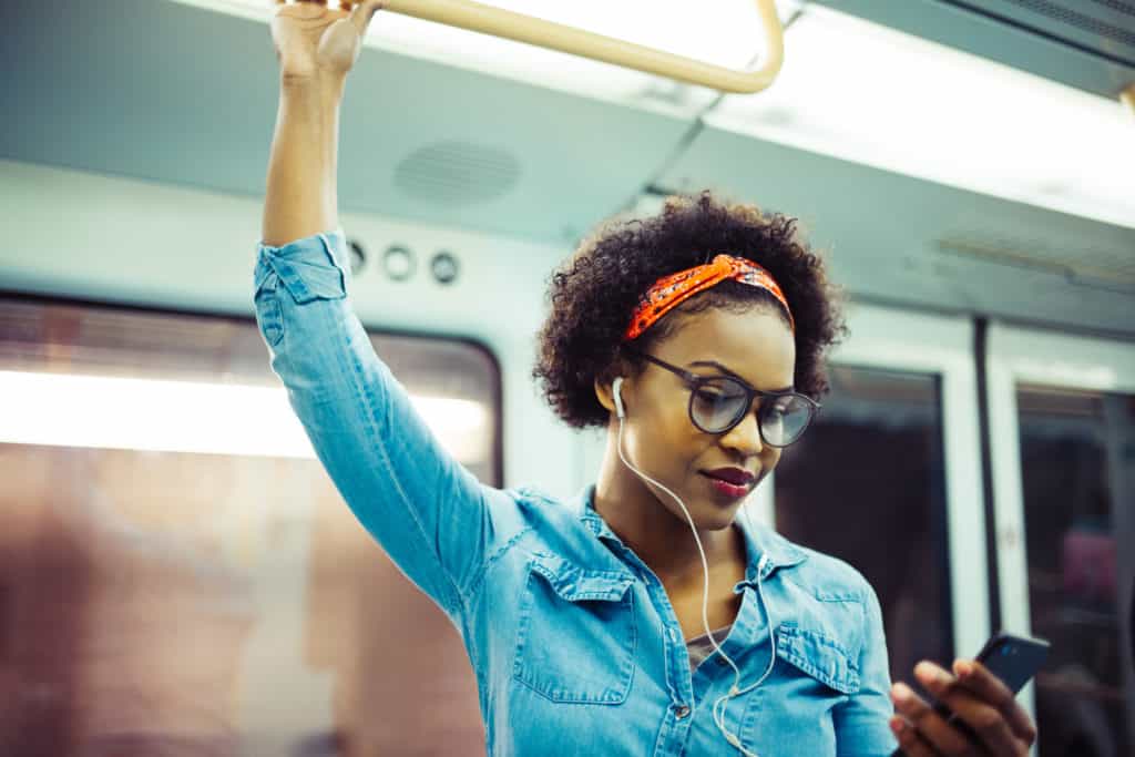 Mulher olha o celular dentro do metrô