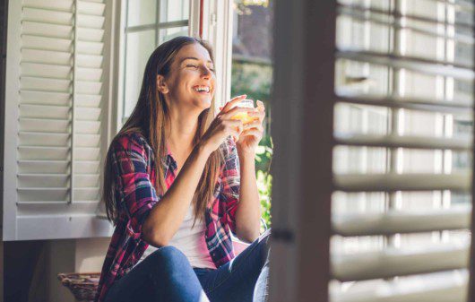 Viver sem ar condicionado - Mulher aproveita ar fresco que entra pela janela de casa