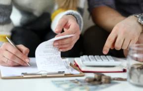 Imagem de um casal fazendo contas com uma calculadora e caderno em cima de uma mesa para ilustrar matéria sobre o que é IPCA