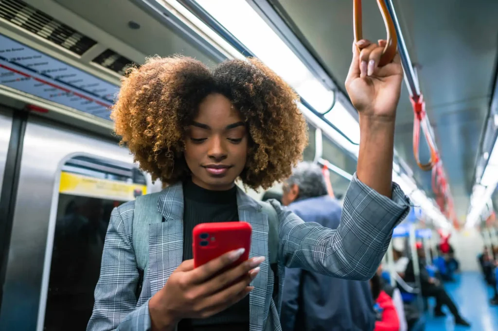Imagem de uma mulher usando o celular no metrô para ilustrar matéria sobre qual é o melhor bairro em São Paulo para morar