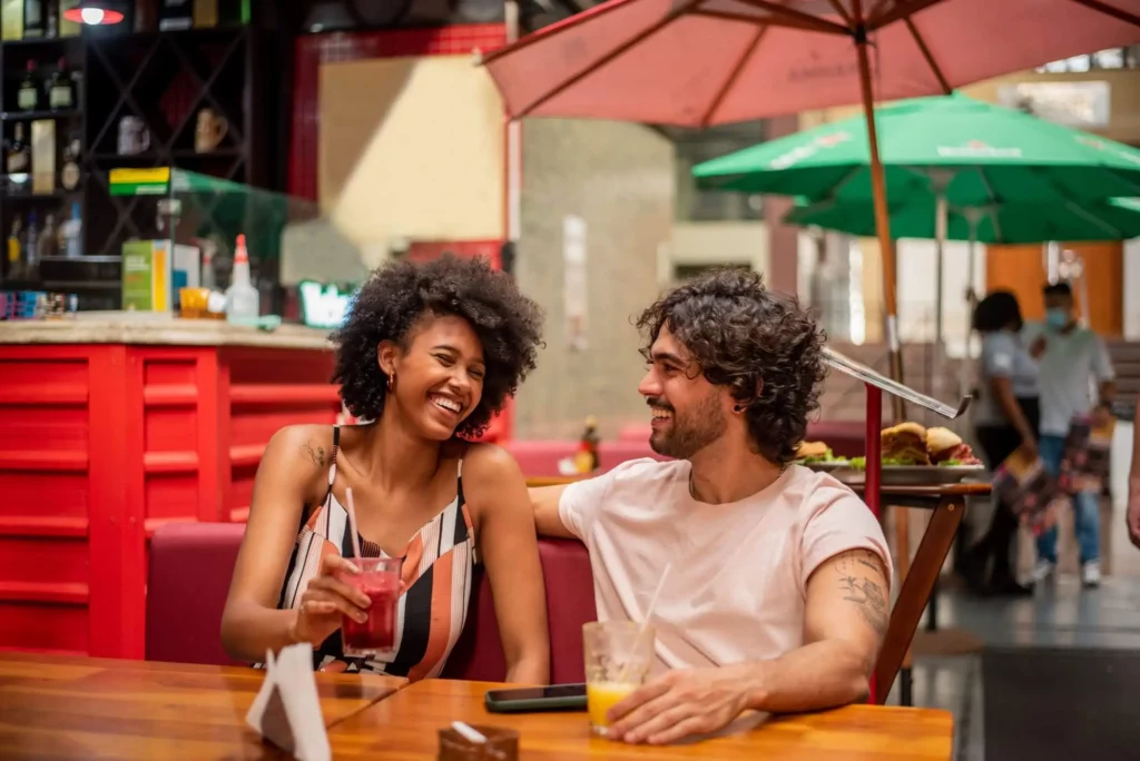 Imagem de um casal sorridente sentados na mesa de um restaurante para ilustrar matéria sobre os melhores bairros em SP para morar