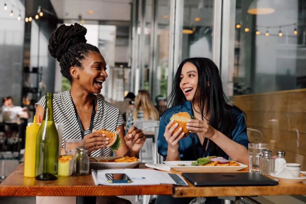 Imagem de duas mulheres conversando e comendo em um restaurante para ilustrar matéria sobre quais são os bairros mais nobres de São Paulo