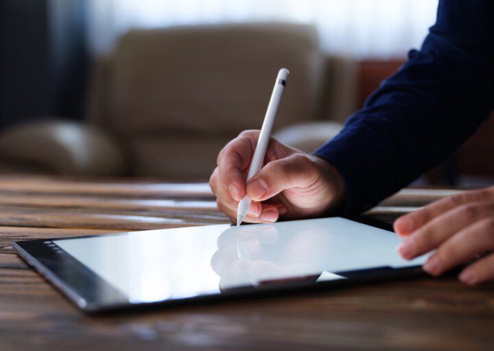 Foto que ilustra matéria sobre tipos de financiamento imobiliário mostra a mão de um homem assinando um contrato digital em um tablet.