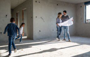 Família feliz analisando planos em seu novo apartamento, em reforma. Imagem disponível em Getty Images.