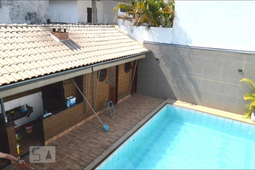 Área externa da casa vista de cima, com visão de uma construção de tijolos e uma piscina