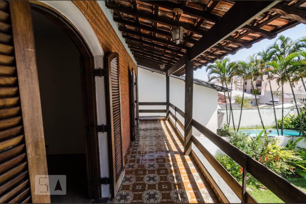 Vista da piscina e do jardim a partir de uma varanda com portas duplas amplas e beirada de madeira