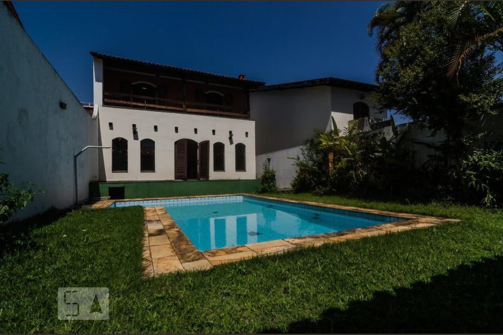 Vista de uma casa e uma piscina em L no jardim