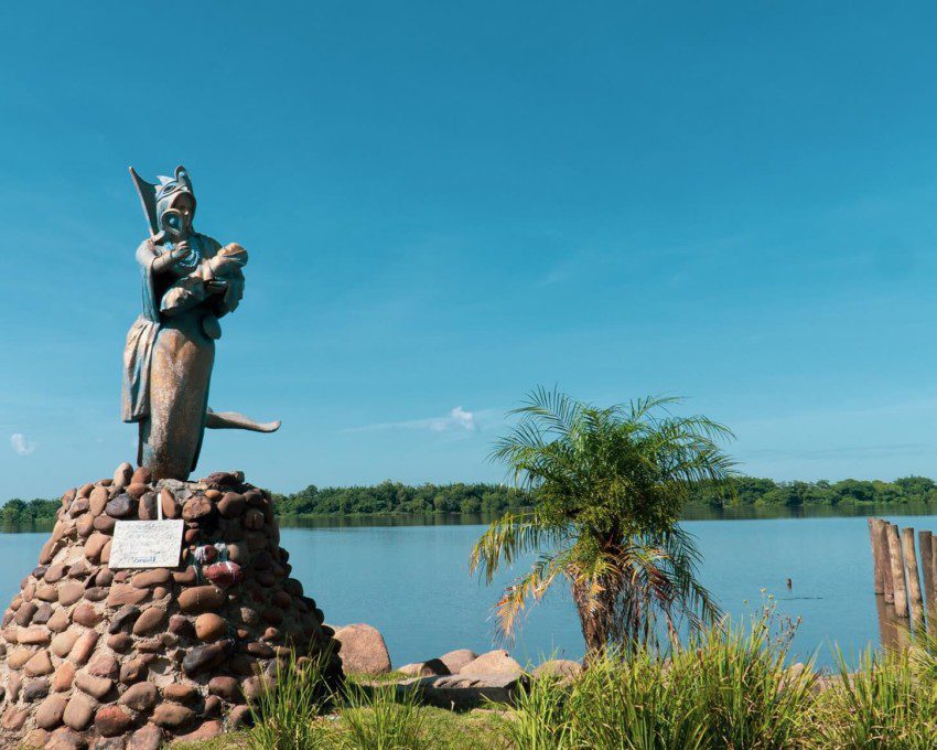 Foto que ilustra matéria sobre as praias de Canoas mostra a Praia do Paquetá, com destaque para a escultura Mãe das Águas, que aparece em primeiro plano, mais à esquerda, com o espelho d’água do Rio ao fundo.