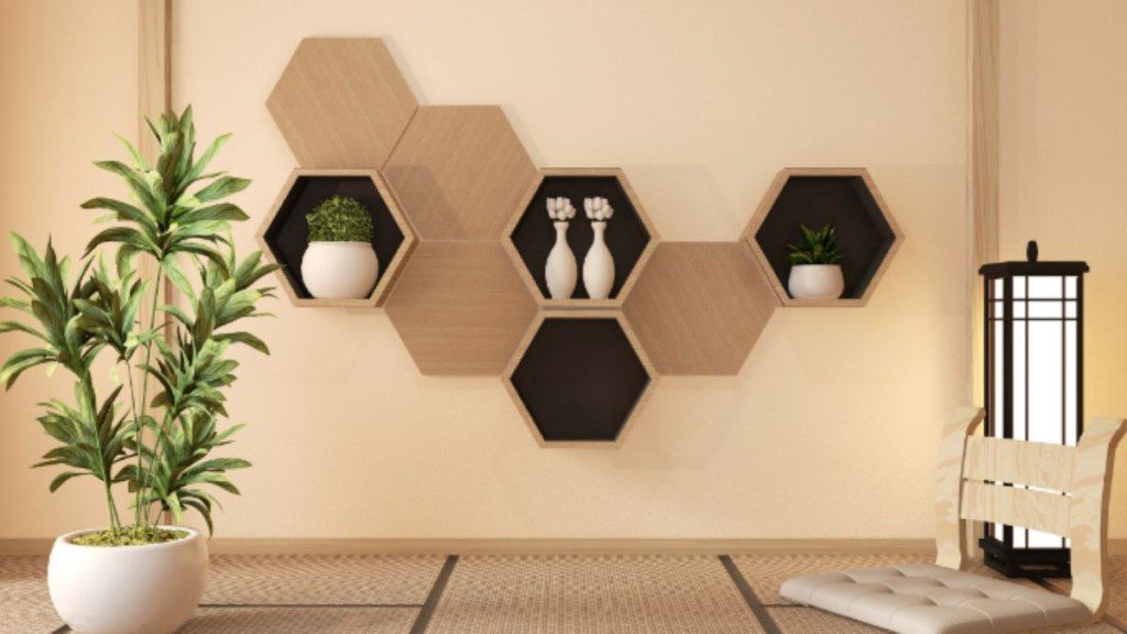 vários nichos hexagonais de parede, alguns com objetos decorativos dentro, outros vazios. No chão, próximo aos nichos à esquerda, há um vaso com uma planta.