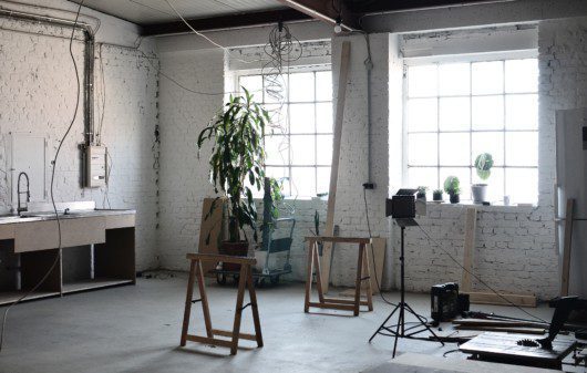 Imagem de um ambiente com tijolinhos na parede em tons de cinza, duas janelas e vários fios elétricos soltos na parede