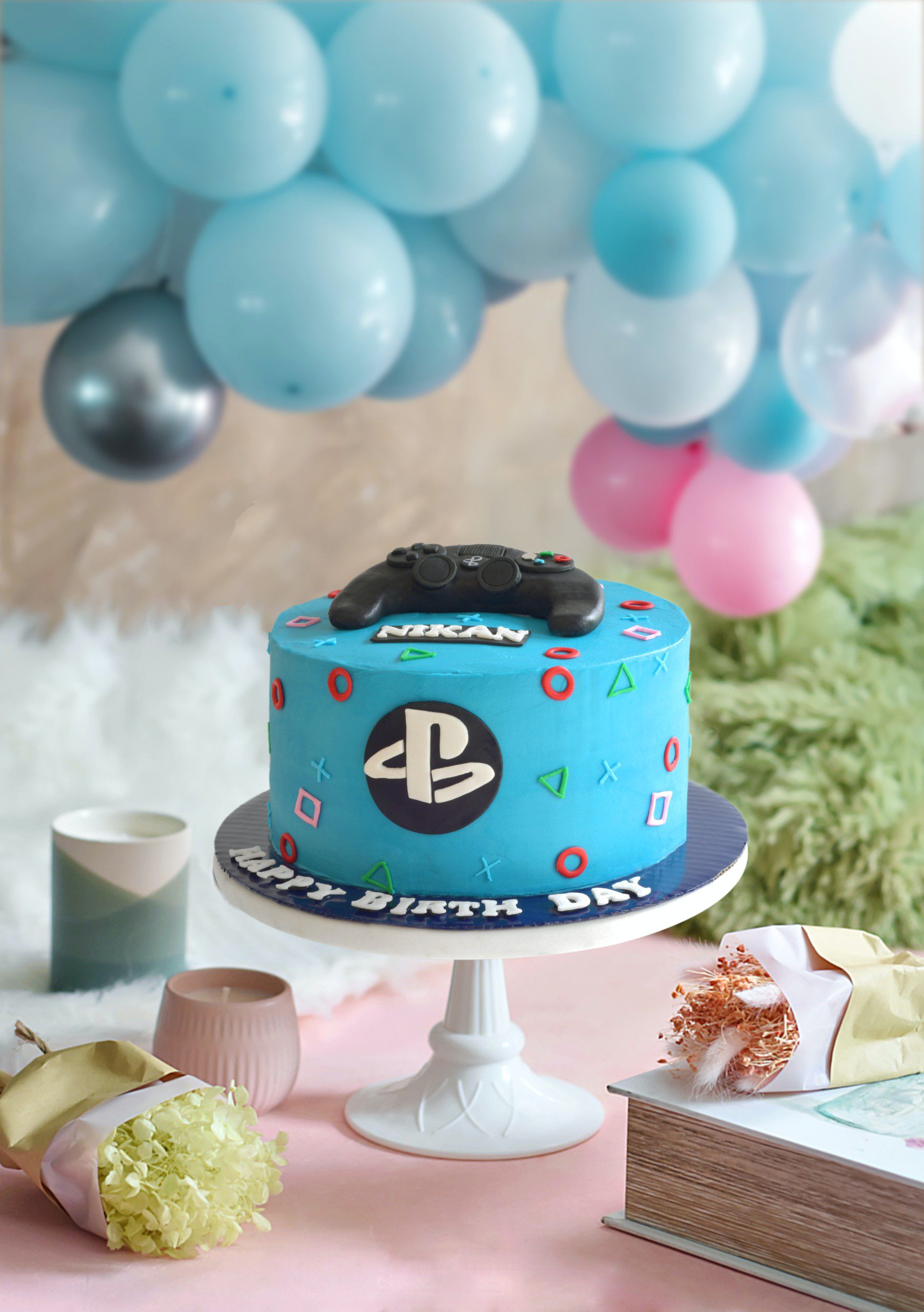 Imagem de uma bolo de aniversário com tema de jogos e Playstation. 