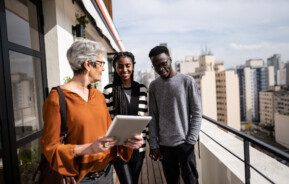 Foto que ilustra matéria sobre Rede QuintoAndar mostra um casal visitando um apartamento com uma corretora de imóveis