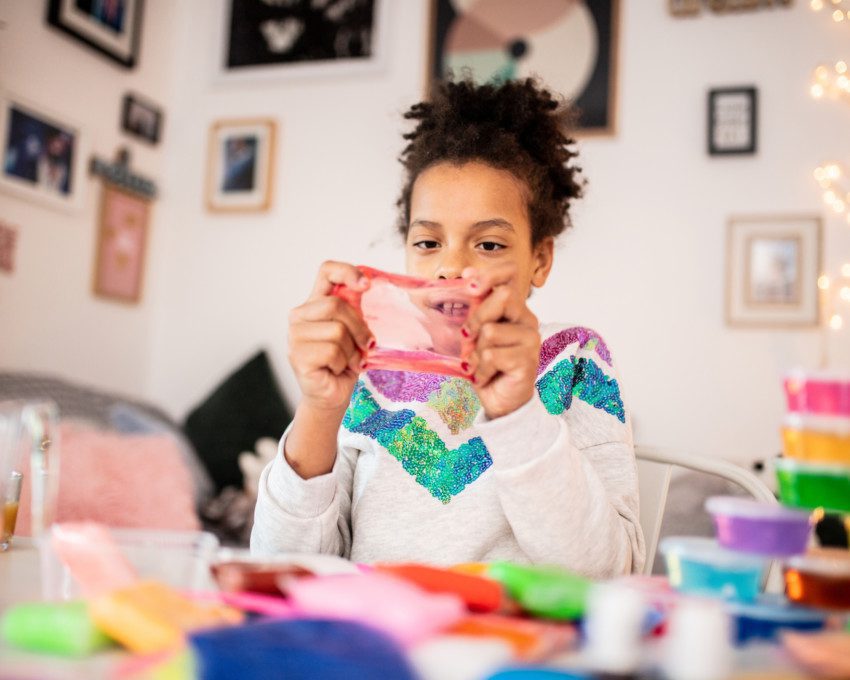 Imagem de uma menina brincando com slime.