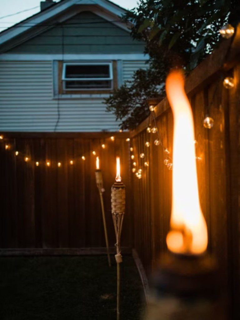 quintal pequeno iluminado por luzes pisca-pisca e por uma vela no fim do dia