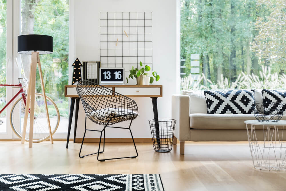 A imagem mostra uma sala com: lustre de chão, poltrona, mesa retangular, sofá, mesa de centro. Há também itens decorativos como tapete, almofadas, relógio e plantas.