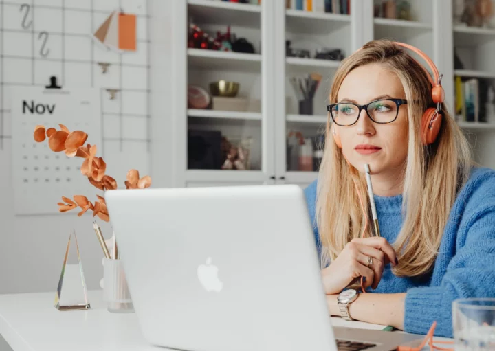 Foto que ilustra matéria sobre imóvel comercial ou residencial mostra uma mulher sentada em frente ao computador com óculos e fones de ouvido com feição concentrada.