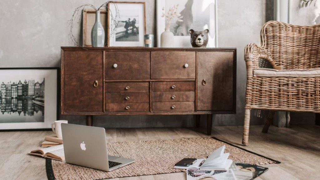 cômoda rústica em quarto com tapete e notebook em cima do tapete, o ambiente tem ar aconchegante