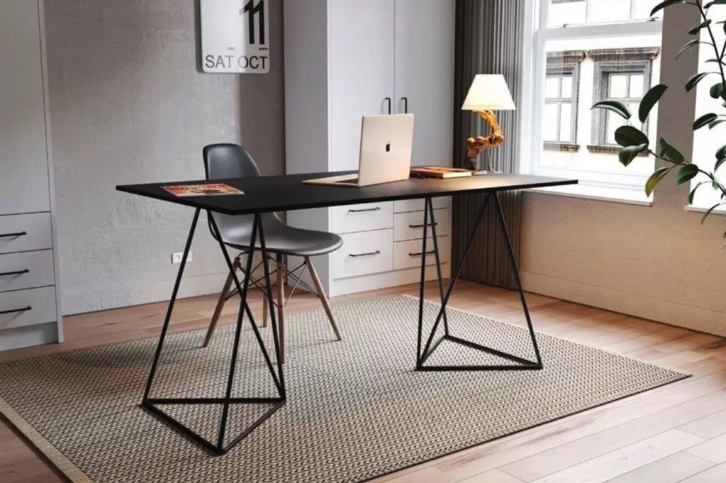 Foto que ilustra matéria sobre decoração de escritório moderno mostra uma mesa de trabalho com tampo de madeira e pés com base triangular.