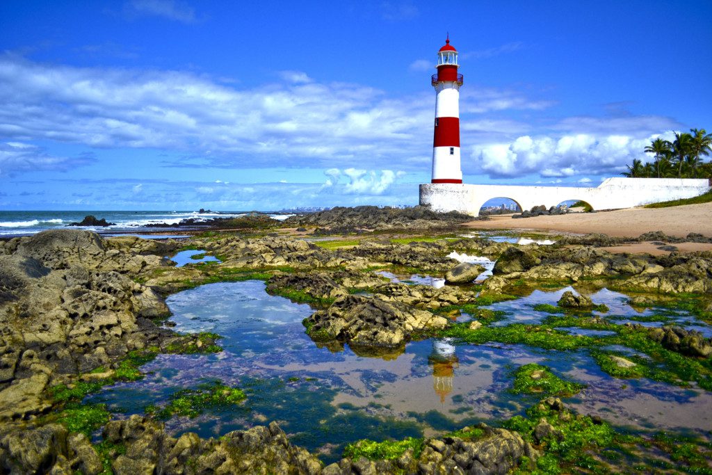 Imagem que ilustra matéria sobre o que fazer em Salvador mostra a praia de Itapuã com a vista do farol de Itapuã.