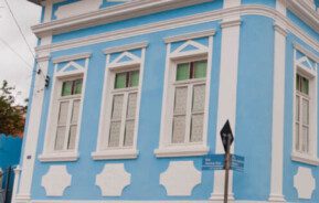 Foto que ilustra matéria sobre onde fica Santana do Parnaíba mostra um casarão histórico, um dos muitos tombados na cidade. A construção é toda azul clara, com detalhes em branco nas janelas e portas.