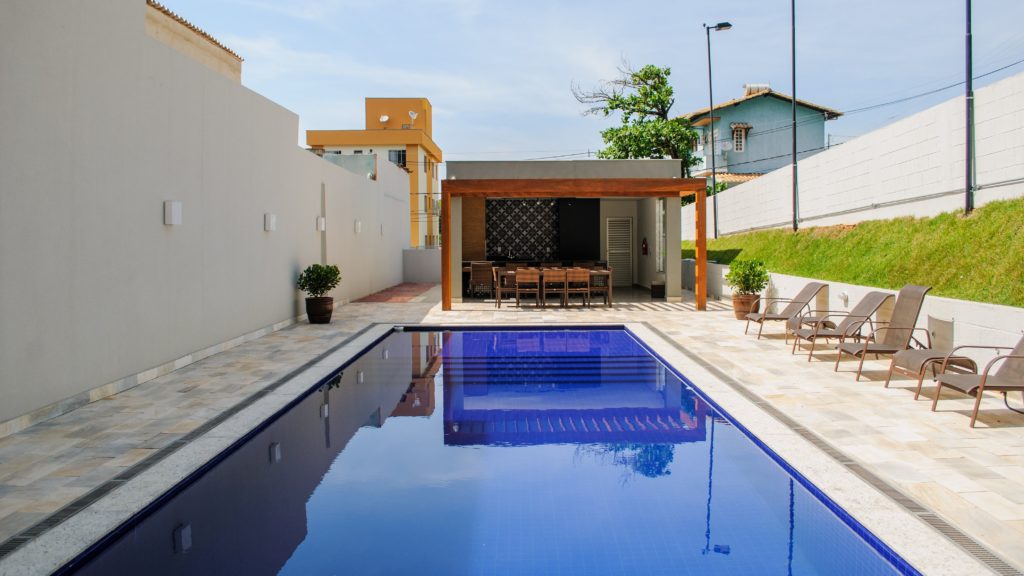 Area gorumet com decoração colonial. Piscina em primeiro plano, mesão com bancada ao fundo. Disponível no pexels