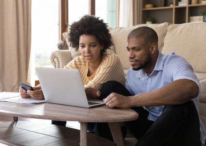 Foto que ilustra matéria sobre como escolher inquilino mostra um homem e uma mulher sentados em frente à um computador que está em uma mesa