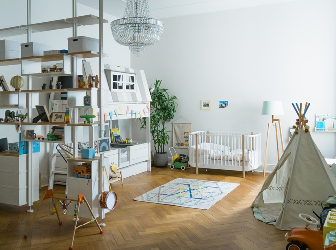 Imagem de um quarto infantil com cama, cabaninha de tecido e berço.