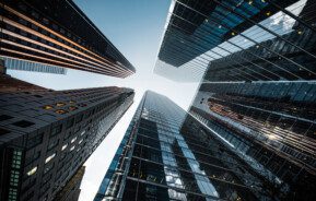 A foto mostra vários prédios grandes vistos de baixo para cima.