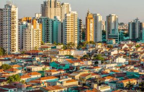 Foto que ilustra matéria sobre tipos de moradia mostra uma parte da cidade de São Paulo com muitas casas em primeiro plano e prédios altos ao fundo.