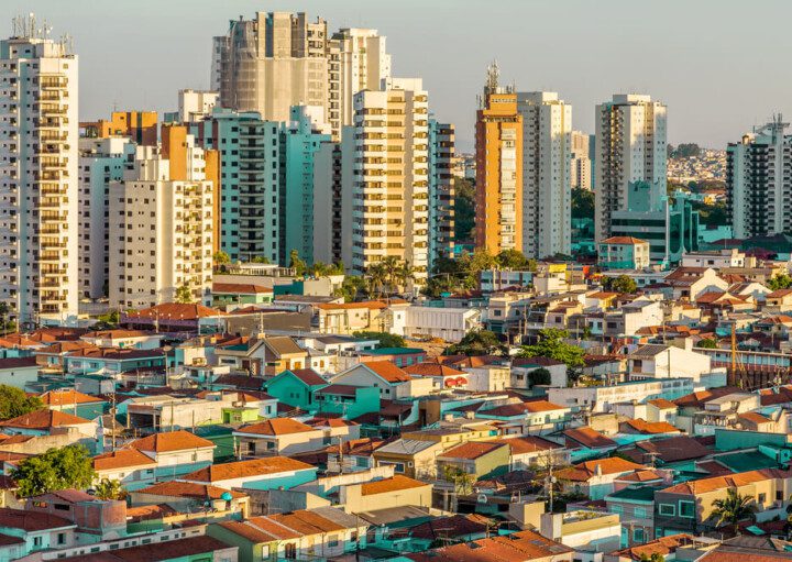 Foto que ilustra matéria sobre tipos de moradia mostra uma parte da cidade de São Paulo com muitas casas em primeiro plano e prédios altos ao fundo.