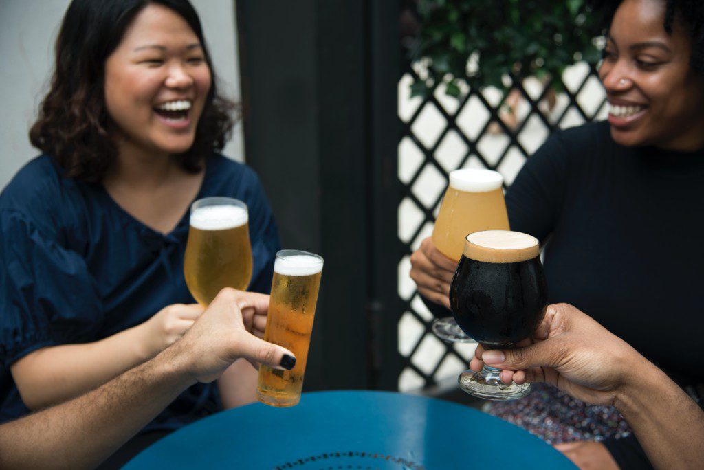 Mulheres brindando e comemorando com diferentes taças de cerveja.