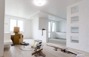 Foto que ilustra matéria sobre quanto custa reformar um apartamento mostra uma sala com algumas caixas, materiais e ferramentas, indicando uma obra.