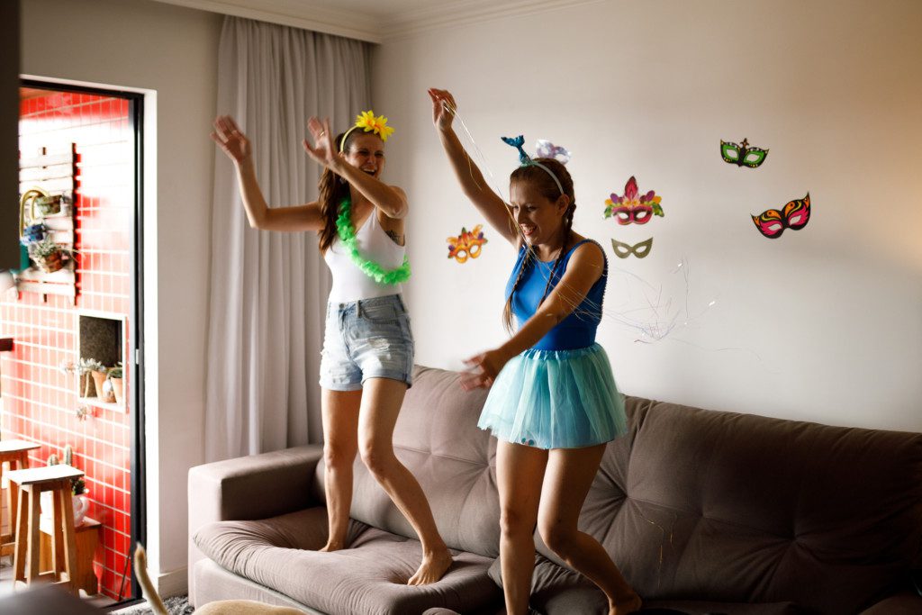 Duas amigas encima do sofá curtindo o carnaval em casa.