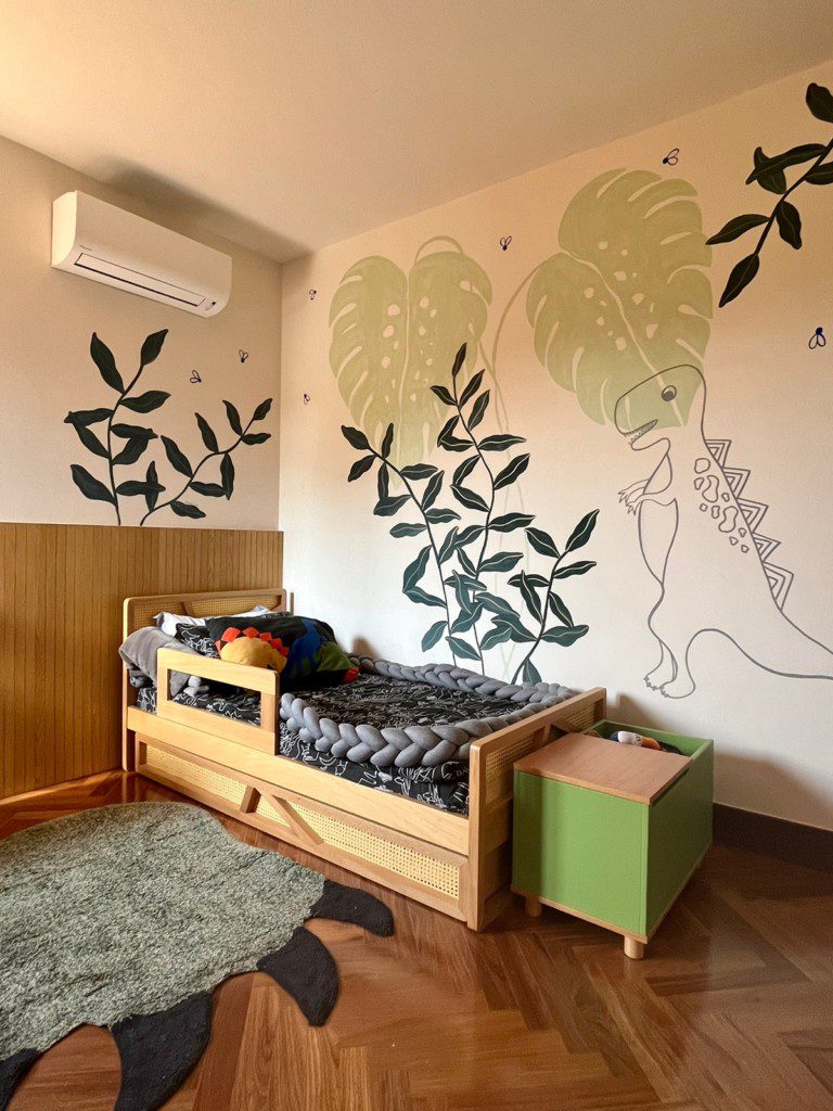 Quarto infantil com parede desenhada no tema dinossauros. 