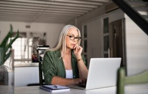 Foto que ilustra matéria sobre planejamento sucessório mostra uma mulher sentada em uma mesa mexendo em um computador