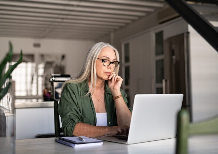 Foto que ilustra matéria sobre planejamento sucessório mostra uma mulher sentada em uma mesa mexendo em um computador