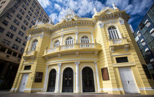 Foto mostra a fachada do Theatro Carlos Gomes em um dia de sol