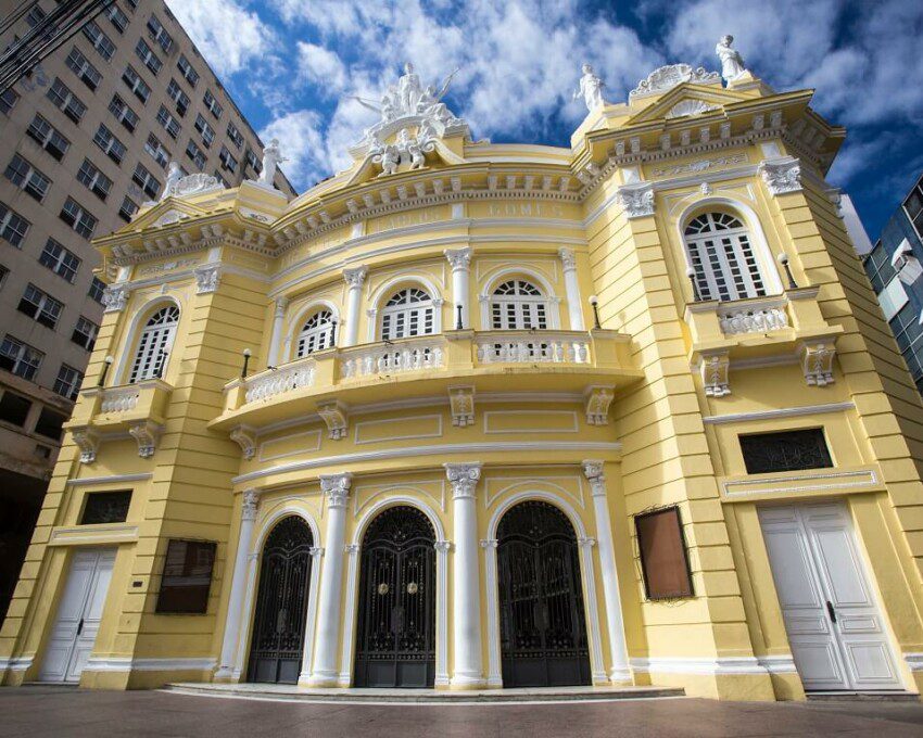 Foto mostra a fachada do Theatro Carlos Gomes em um dia de sol