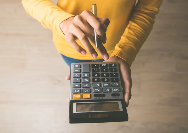 Mulher segurando uma calculadora.