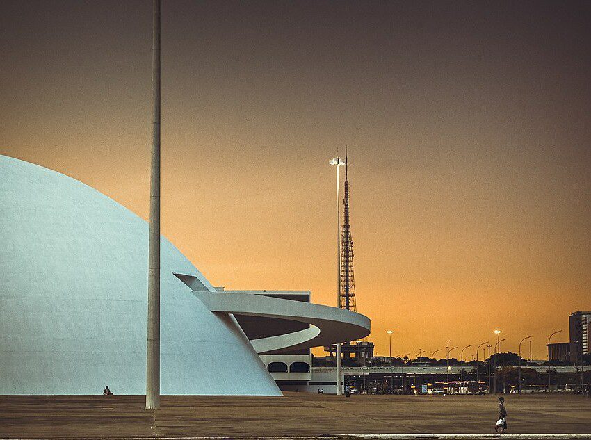 Foto mostra a lateral do Compplexo Cultural da República com o céu alaranjado do cair da noite ao fundo