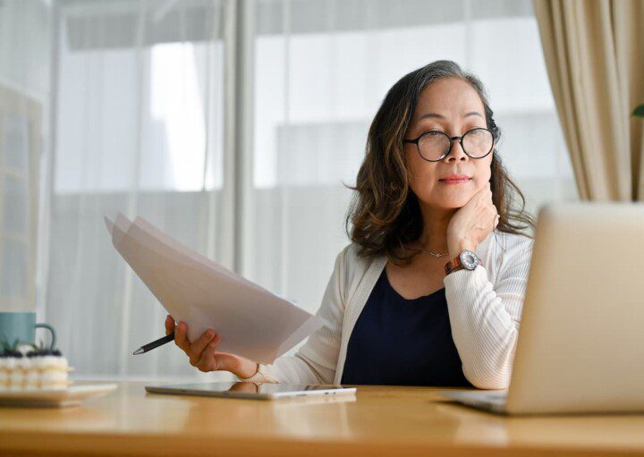 Mulher asiática de meia idade concentrada usando notebook.