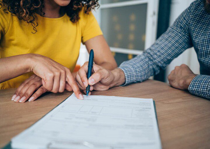 Homem e uma mulher assinam a renovação do contrato de aluguel.