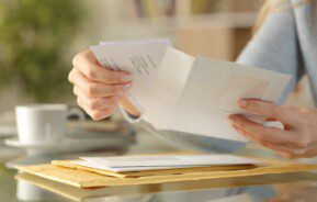 Mãos com características femininas abrem um envelope de carta.