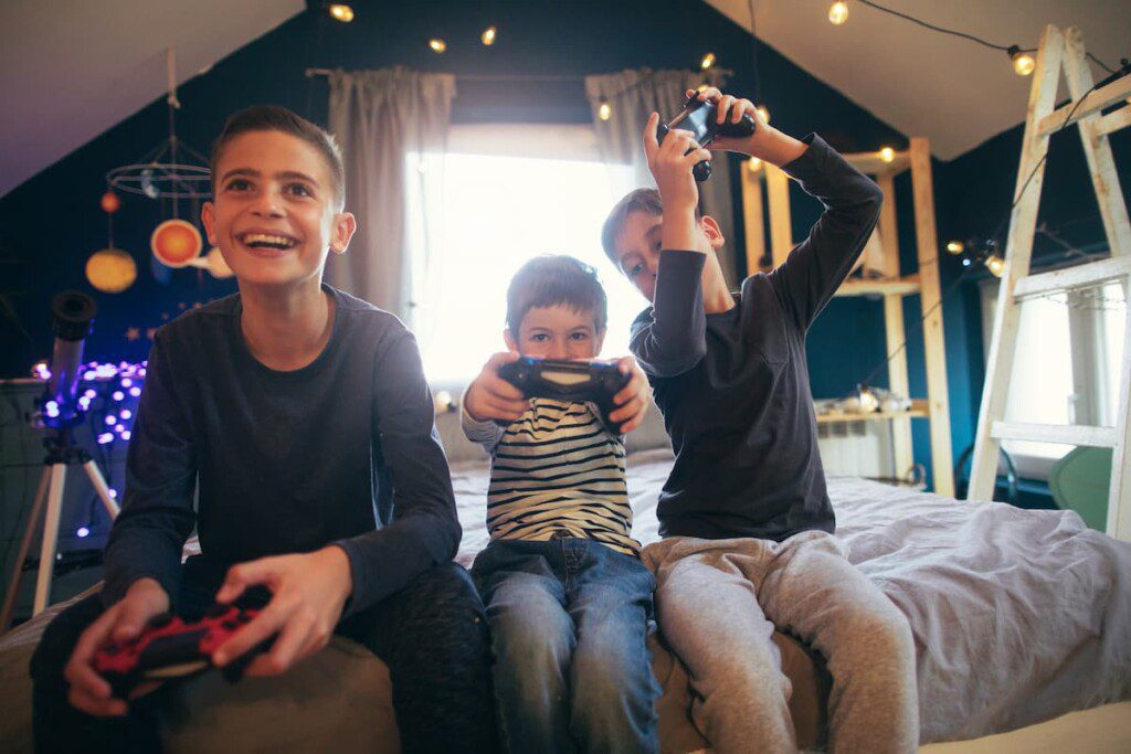 Três irmãos, ainda crianças, jogando videogame no quarto.