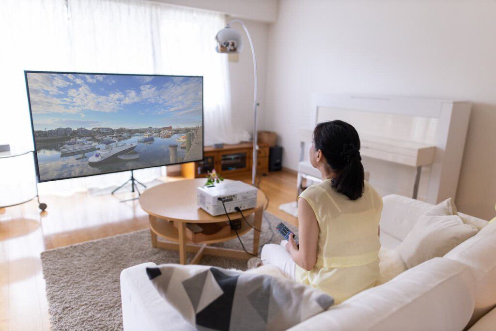 Sala de cinema em casa improvisada, com projetor e tela de projeção.