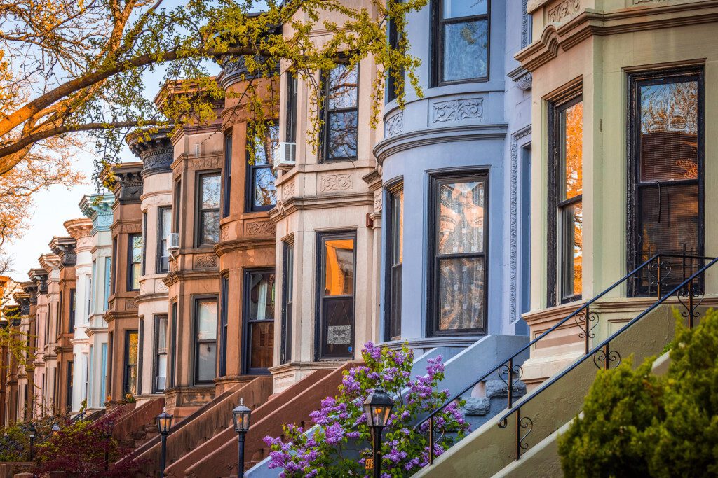 Imagem panorâmica de um conjunto de townhouses coloridas com arquitetura padronizada e algumas plantas na frente de cada uma delas