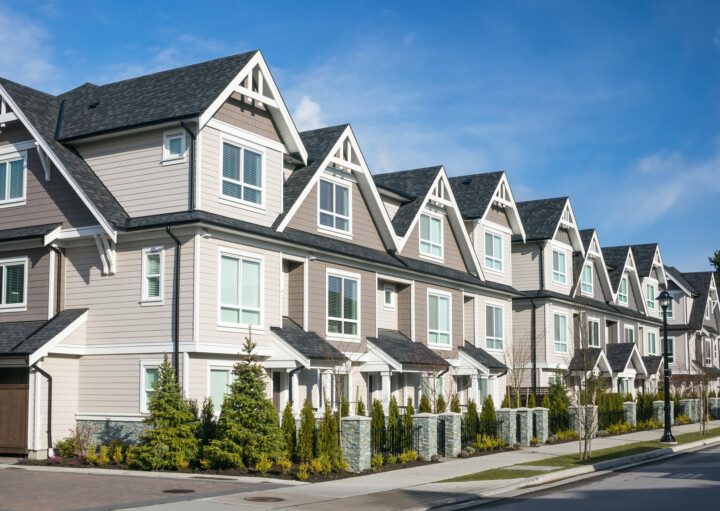 Imagem panorâmica de um conjunto de townhouses modernas com fachadas na cor bege e marrom