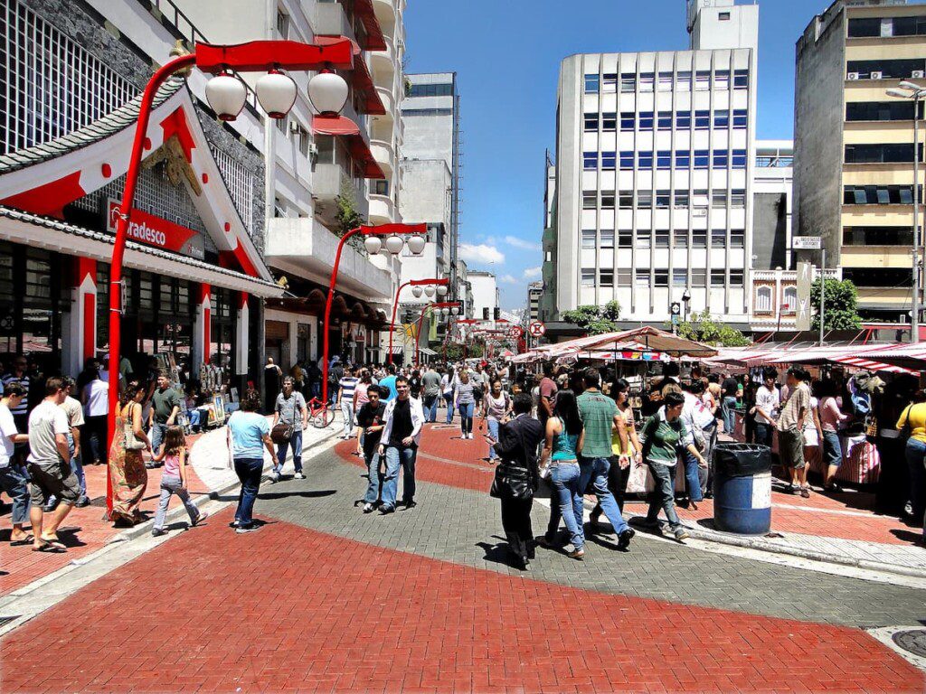 Feira na Praça da Liberdade, em São Paulo. É possível notar traços da arquitetura japonesa nos prédios e mobiliários urbanos.