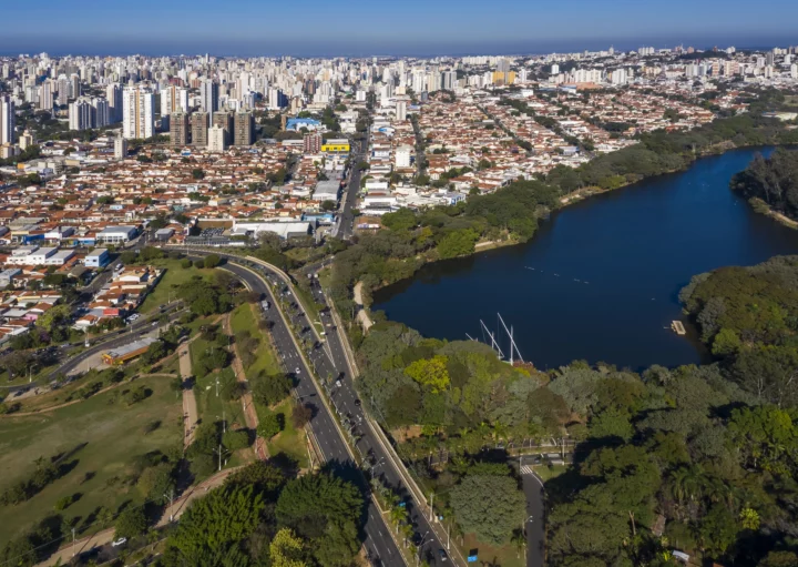 Imagem aérea da Lagoa do Taquaral e de parte da cidade de Campinas ao amanhecer para ilustrar matéria sobre as vantagens e desvantagens de morar em Campinas