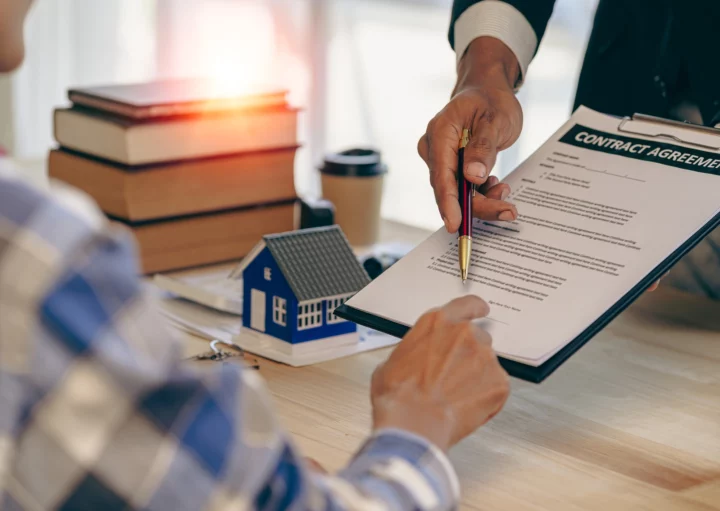 Imagem de um homem entregando uma prancheta com documento e uma caneta para outro homem vestido de azul para ilustrar matéria sobre declaração de residência para inquilino